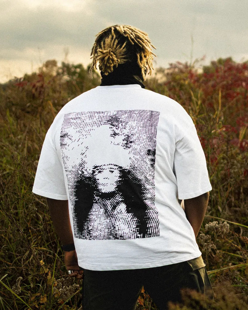 Person wearing a white t-shirt with a graphic design in a field