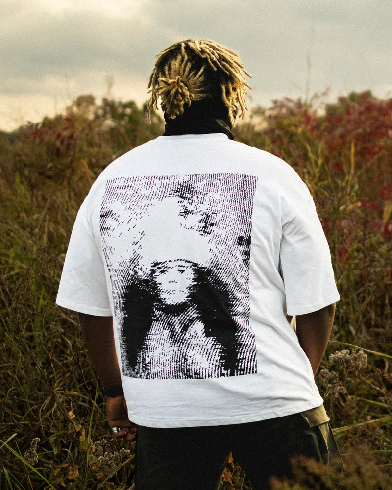 Person wearing a white t-shirt with a graphic design in a field